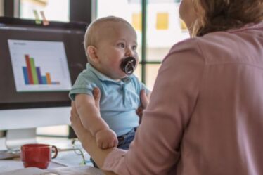 Online Geld Verdienen Mama houdt Baby vast - thuiswerken, remote werken, plaats onafhankelijk