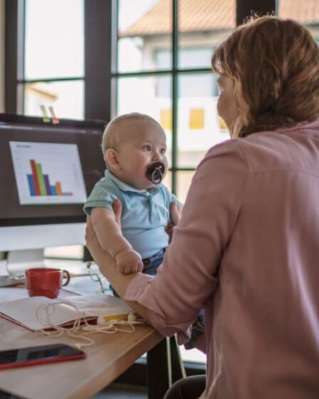 Online Geld Verdienen Mama houdt Baby vast - thuiswerken, remote werken, plaats onafhankelijk