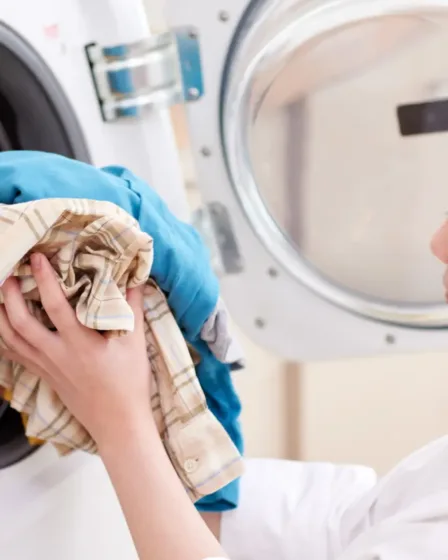 Vrouw stopt kleren in de wasmachine, ze heeft eerder zelf haar goedkope en duurzame wasmiddel gemaakt