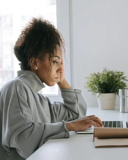 (zwarte) vrouw zit achter de laptop en denkt na over het aflossen van haar studieschuld want ze wil een hypotheek aanvragen.