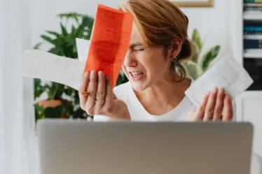 Geldstress bij dame achter haar laptop die eerst snel geld wilde lenen maar zich toch bedenkt na het lezen van de blog over de risico's en regels daarvan