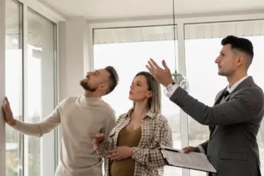 Een koppel: man en een zwangere vrouw bezichtigen of bekijken een woning van binnen en worden geholpen door een makelaar. Zullen ze een huis kopen of toch blijven huren?